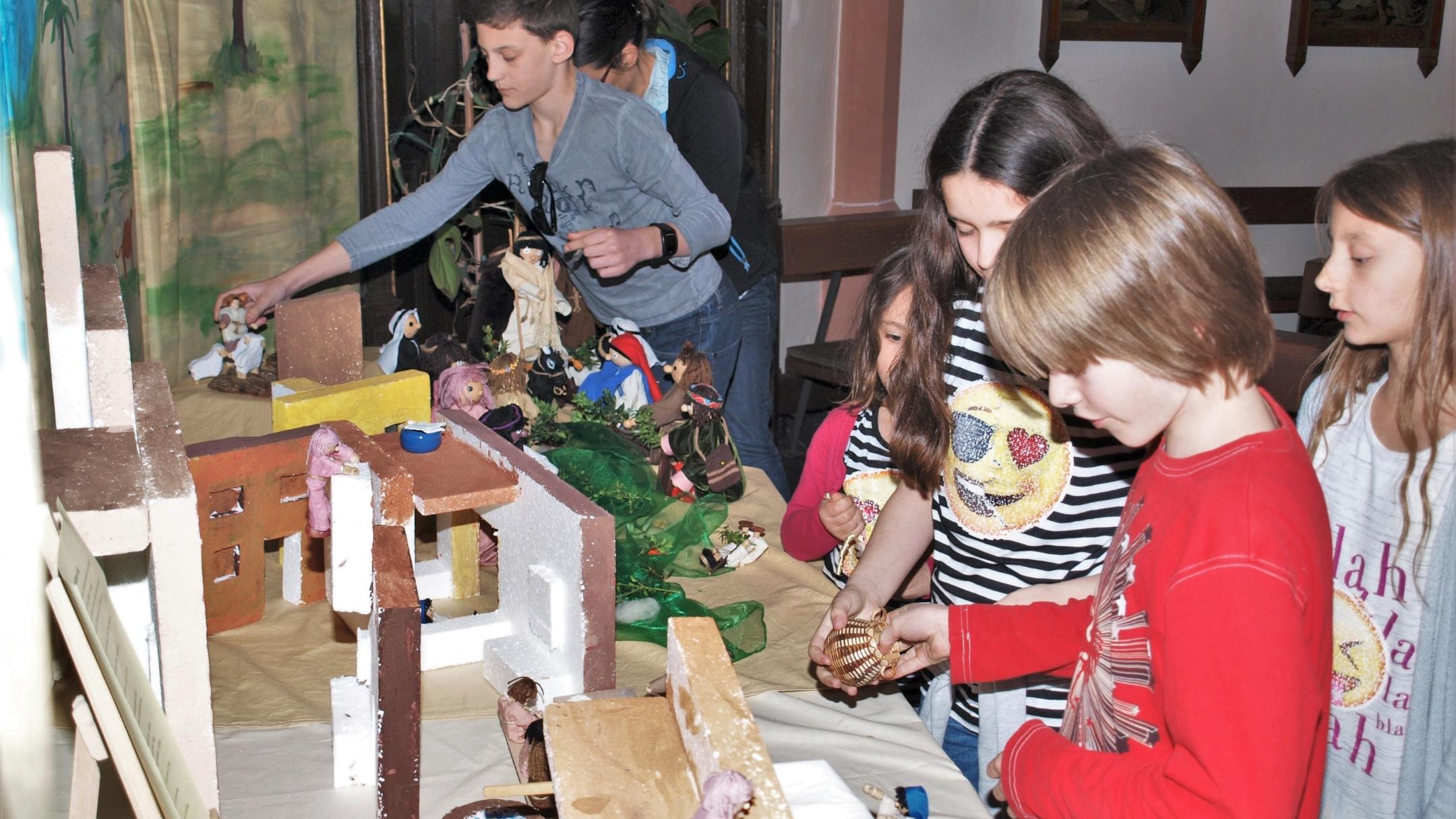 Einzug Jesu in Jerusalem: Mit biblischen Figuren, einer Eselin und „Palmzweigen“ stellen die Kinder in der Bibel-Ecke in der St.-Maternus-Kirche den zuvor gelesenen Evangeliumstext nach.