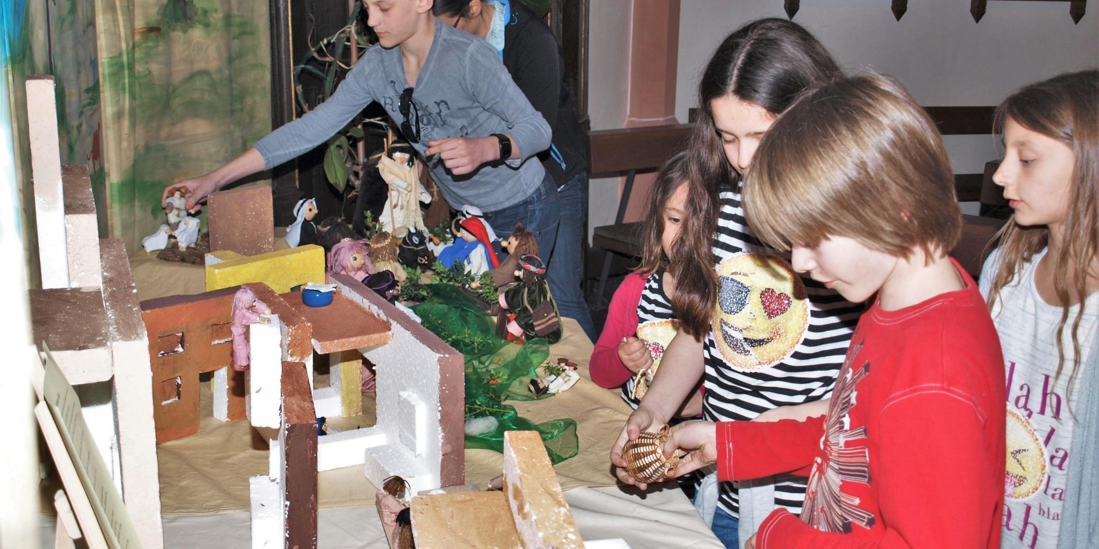 Einzug Jesu in Jerusalem: Mit biblischen Figuren, einer Eselin und „Palmzweigen“ stellen die Kinder in der Bibel-Ecke in der St.-Maternus-Kirche den zuvor gelesenen Evangeliumstext nach.