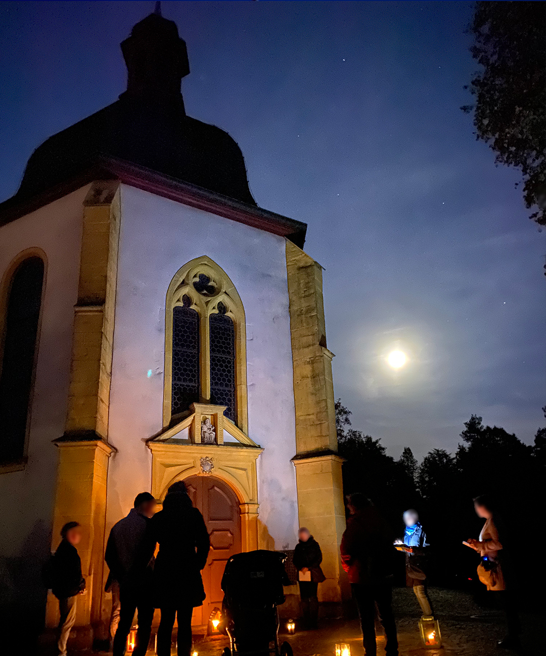 Die Gruppe hält kurz inne vor der Kapelle auf dem Friedhof St. Matthias, bevor sie weiterzieht zur Grabstätte der Sternenkinder