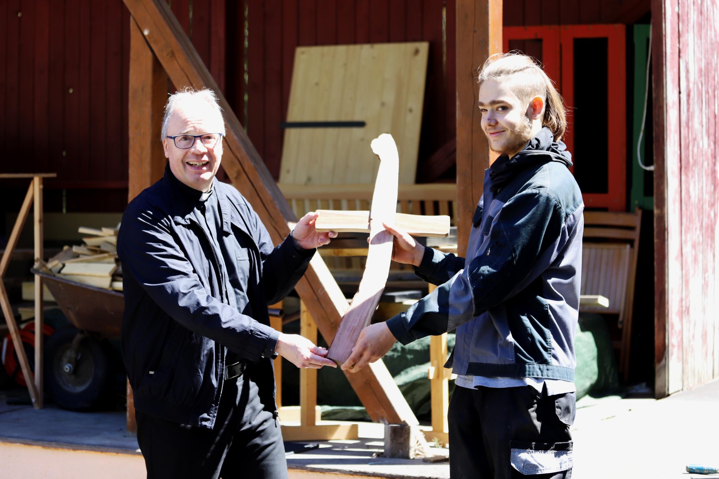 Stolz zeigen Marlon und Bischof Ackermann das Holzkreuz, das sie gebaut haben.