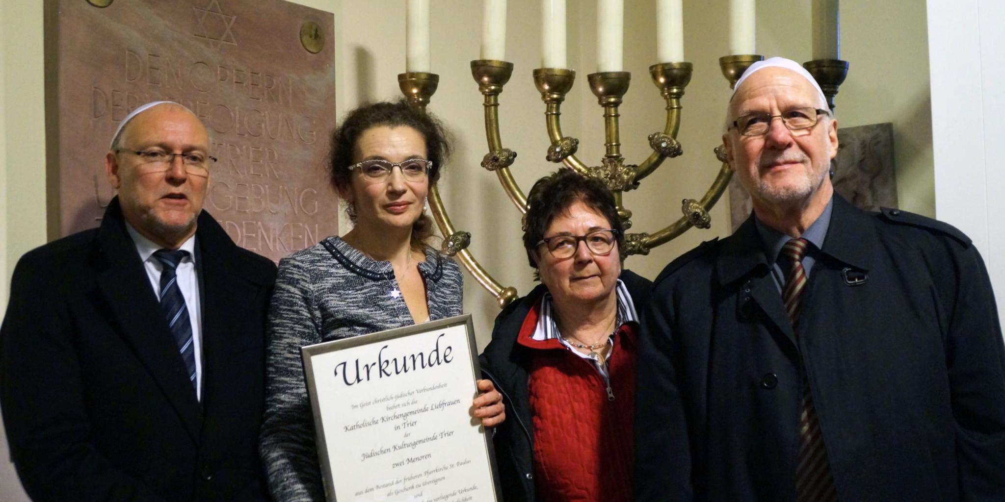 Zwei siebenarmige Leuchter haben ihren Weg aus der Trierer Pauluskirche in die Synagoge gefunden. Darüber freuen sich Ferdinand Häckmanns, Ricarda Kuhner und Thomas Schiffler, Mitglieder des Verwaltungsrates Liebfrauen, (von rechts) und Jeanna Bakal, Vorsitzende der jüdischen Kultusgemeinde Trier (mit Urkunde).