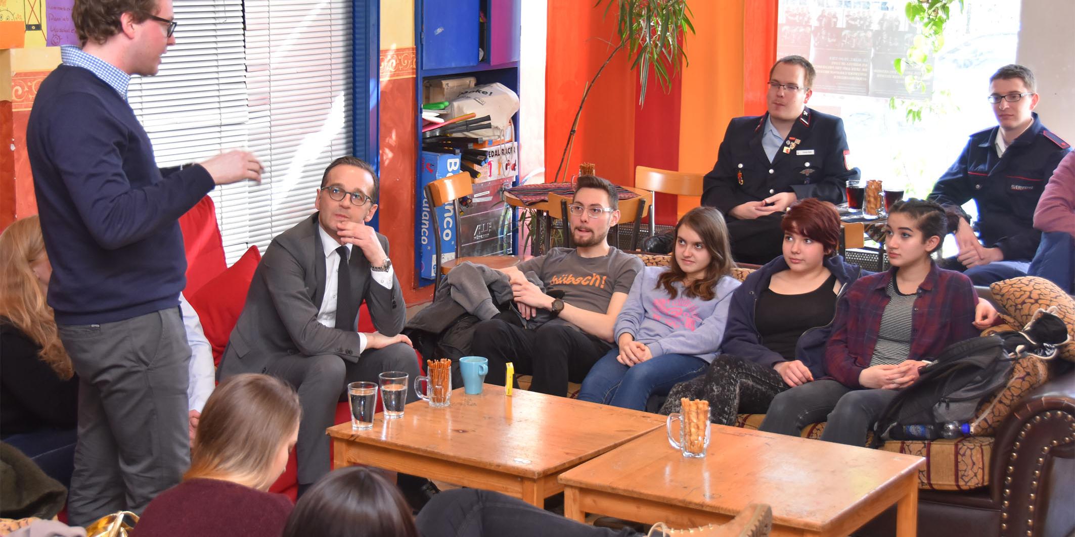 Der Leiter des Café Exodus Maximilian Schmitt (l.) begrüßt Bundesjustizminister Heiko Maas (2.v.l.) zu dem Gespräch mit Jugendlichen.