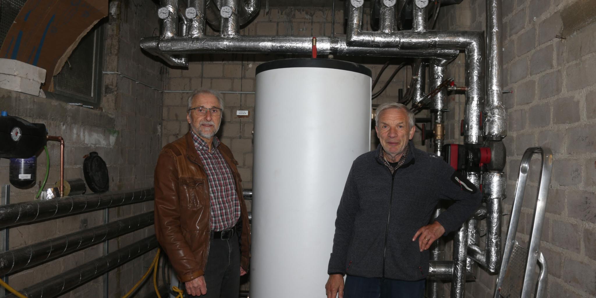 Die Mitglieder des Verwaltungsrats Gerhard Bierschbach (links) und Hans-Josef Gerharz am Pufferspeicher im Technikraum der Pfarrkirche in Nachtsheim. Foto: Elvira Bell