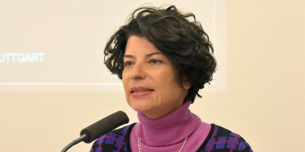 Eine Frau mit dunklen Haaren spricht in ein Mikrofon