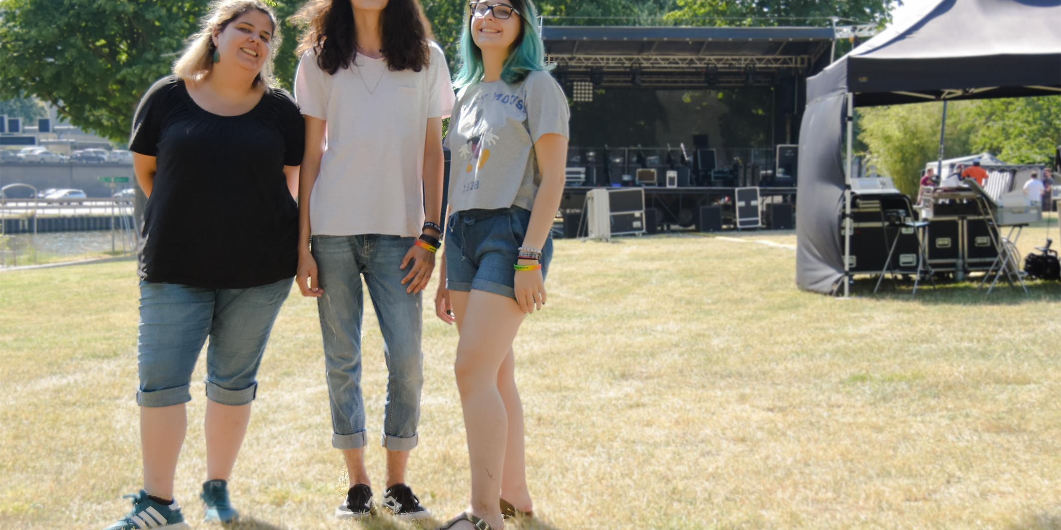 BU: (v.l.) Hannan Chalabi, Sascha Aleksandrov und Andreea Croitoru vor der Bühne auf der Rockwiese während des Aufbaus.