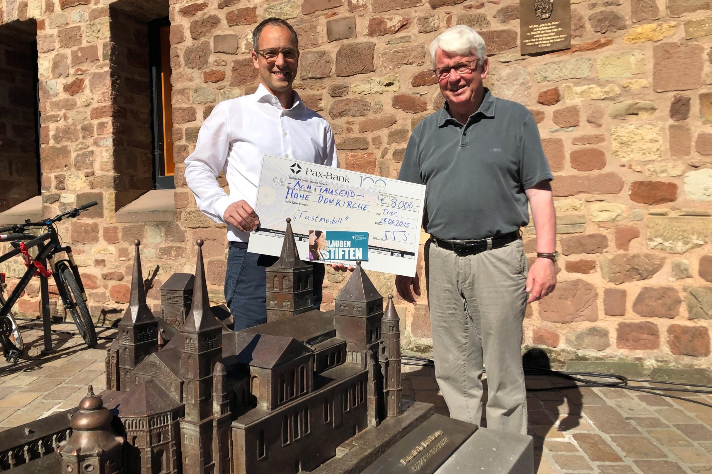 Thomas Theis übergibt im Namen der Bischof Stein Stiftung, in dessen Vorstand er als Leiter des Zentrums für Stiftungen und Fundraising im Bistum Trier Mitglied ist, einen Scheck über 8.000 Euro.