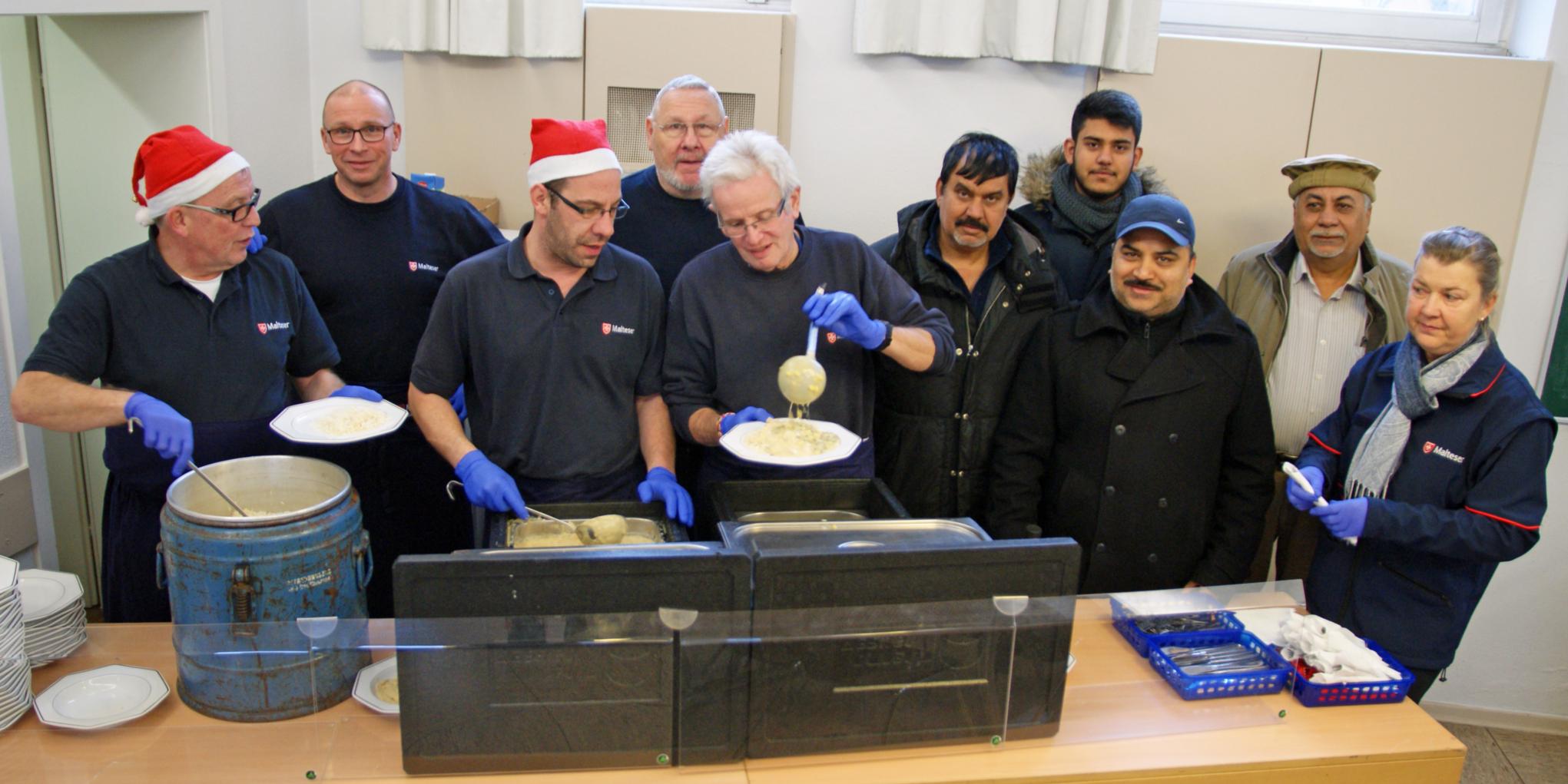 Malteser geben Essen aus und die muslimischen Gäste sind interessierte Beobachter