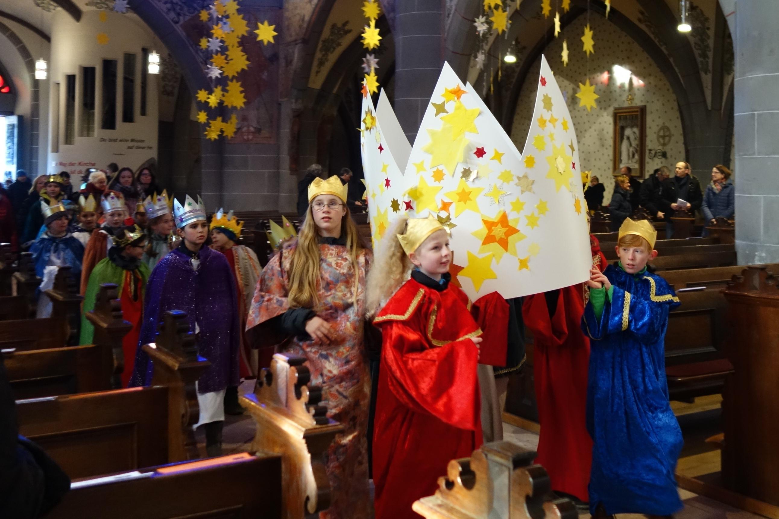 Die Sternsinger tragen eine große Krone in die Pfarrkirche.