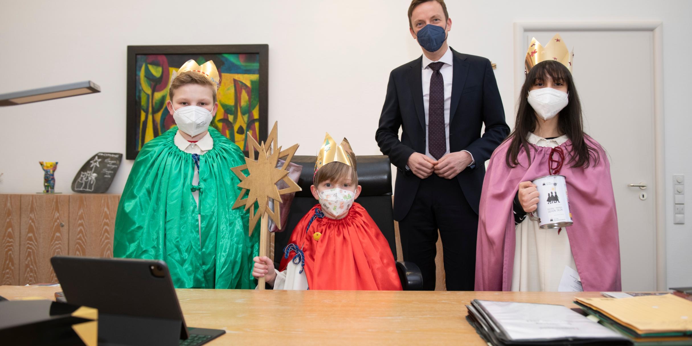 Die Sternsinger Leander, Elian und Maria Virginia mit Ministerpräsident Hans in seinem Büro. Foto: Jennifer Weyland/Staatskanzlei