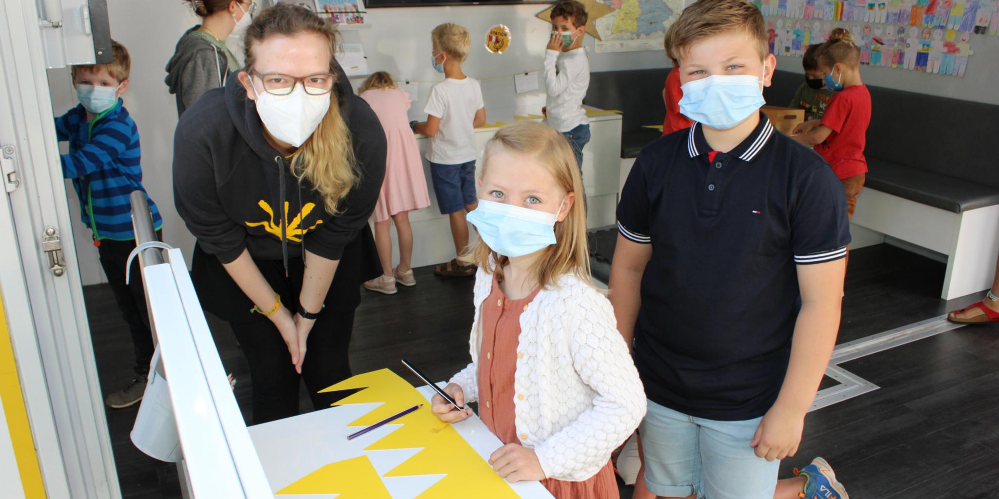 Isabell Mahler vom Kindermissionswerk bastelt mit Lena und Jan ganz persönliche Kronen.