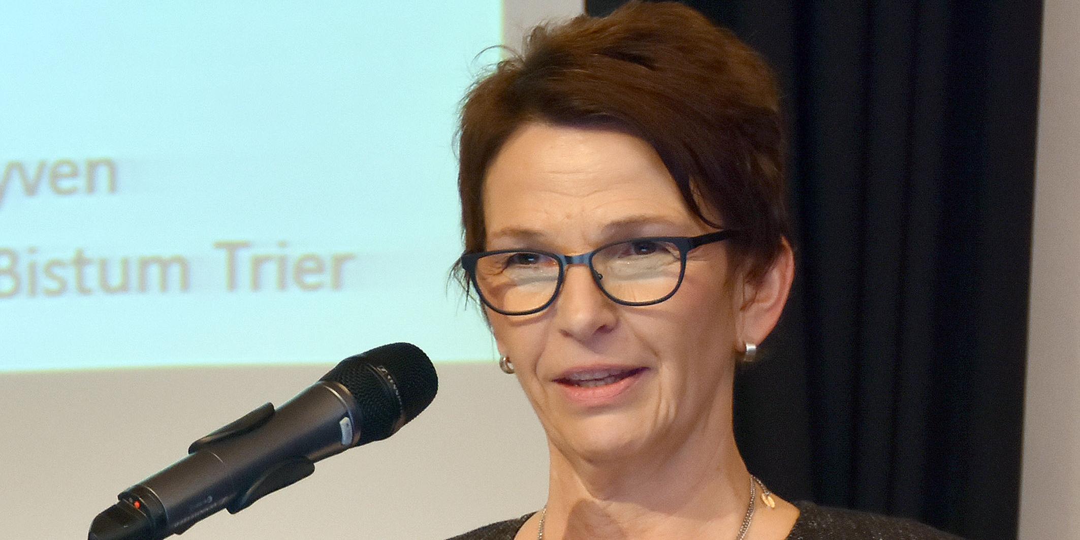 Eine Frau mit Brille spricht in ein Mikrofon.