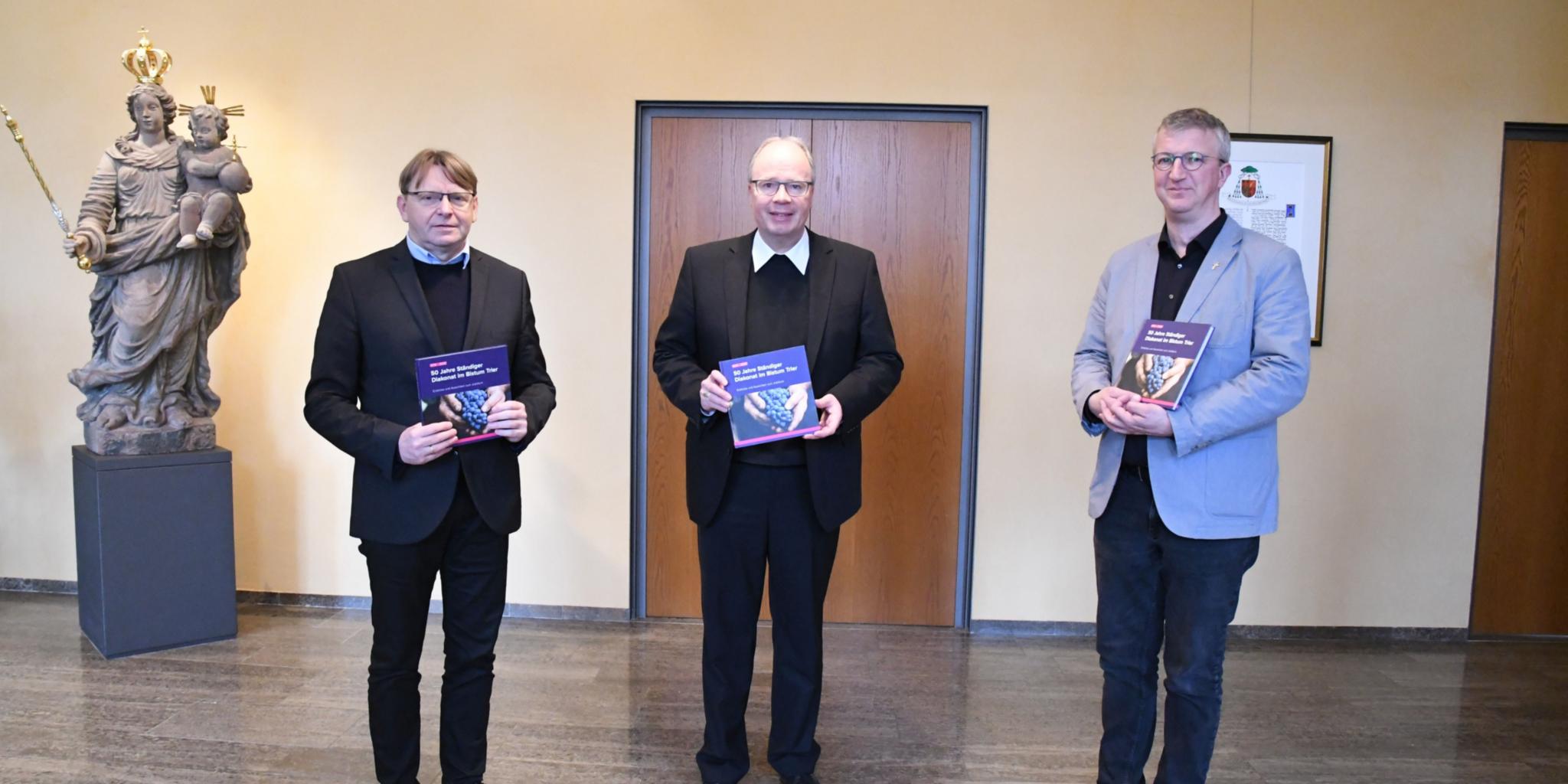 Die Bischöflichen Beauftragten Stefan Stürmer und Axel Berger überreichen Bischof Dr. Stephan Ackermann das Buch zu „50 Jahre Ständiger Diakonat im Bistum Trier.“ Foto: Zeljko Jakobovac