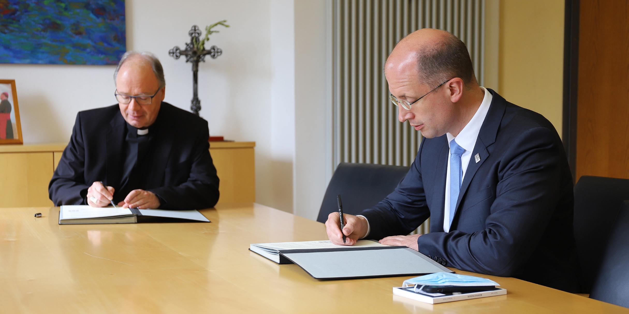 Bischof Ackermann (li.) und Präses Latzel unterzeichnen die Vereinbarung zur konfessionellen Kooperation beim Religionsunterricht (Foto: Bistum Trier/Inge Hülpes)