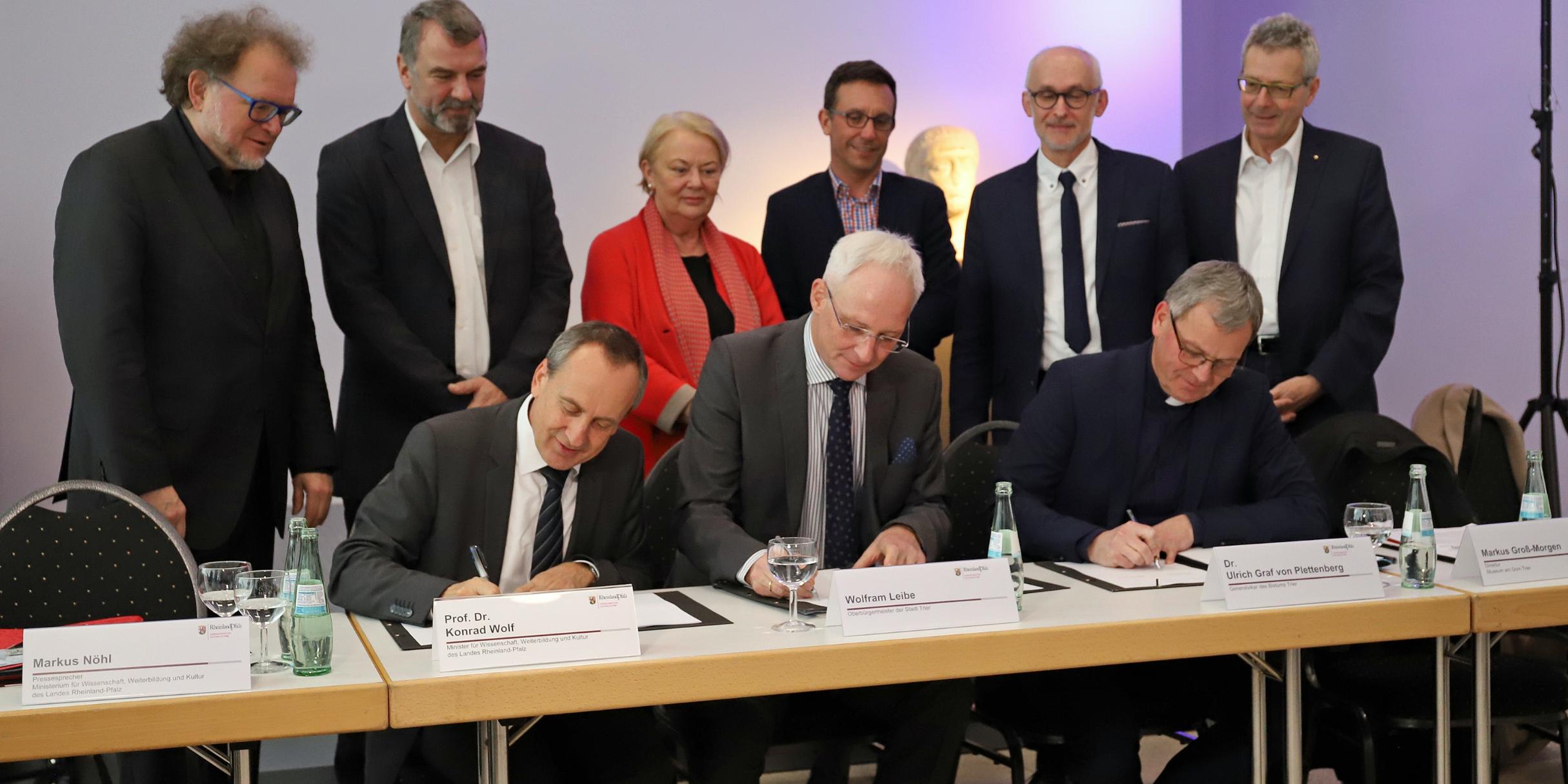 Minister Prof. Dr. Konrad Wolf, Oberbürgermeister Wolfram Leibe und Generalvikar Dr. Ulrich Graf von Plettenberg (vorne sitzende von links). Hinten von links: Thomas Metz, Generaldirektor Kulturelles Erbe Rheinland-Pfalz, Dr. Marcus Reuter, Direktor des Rheinischen Landesmuseums Trier, Dr. Elisabeth Dühr, Direktorin des Stadtmuseums, Thomas Schmitt, Kulturdezernent der Stadt Trier, Markus Groß-Morgen, Leiter des Museums am Dom, und Prof. Dr. Michael Embach, Leiter Stadtbibliothek/Stadtarchiv Trier.