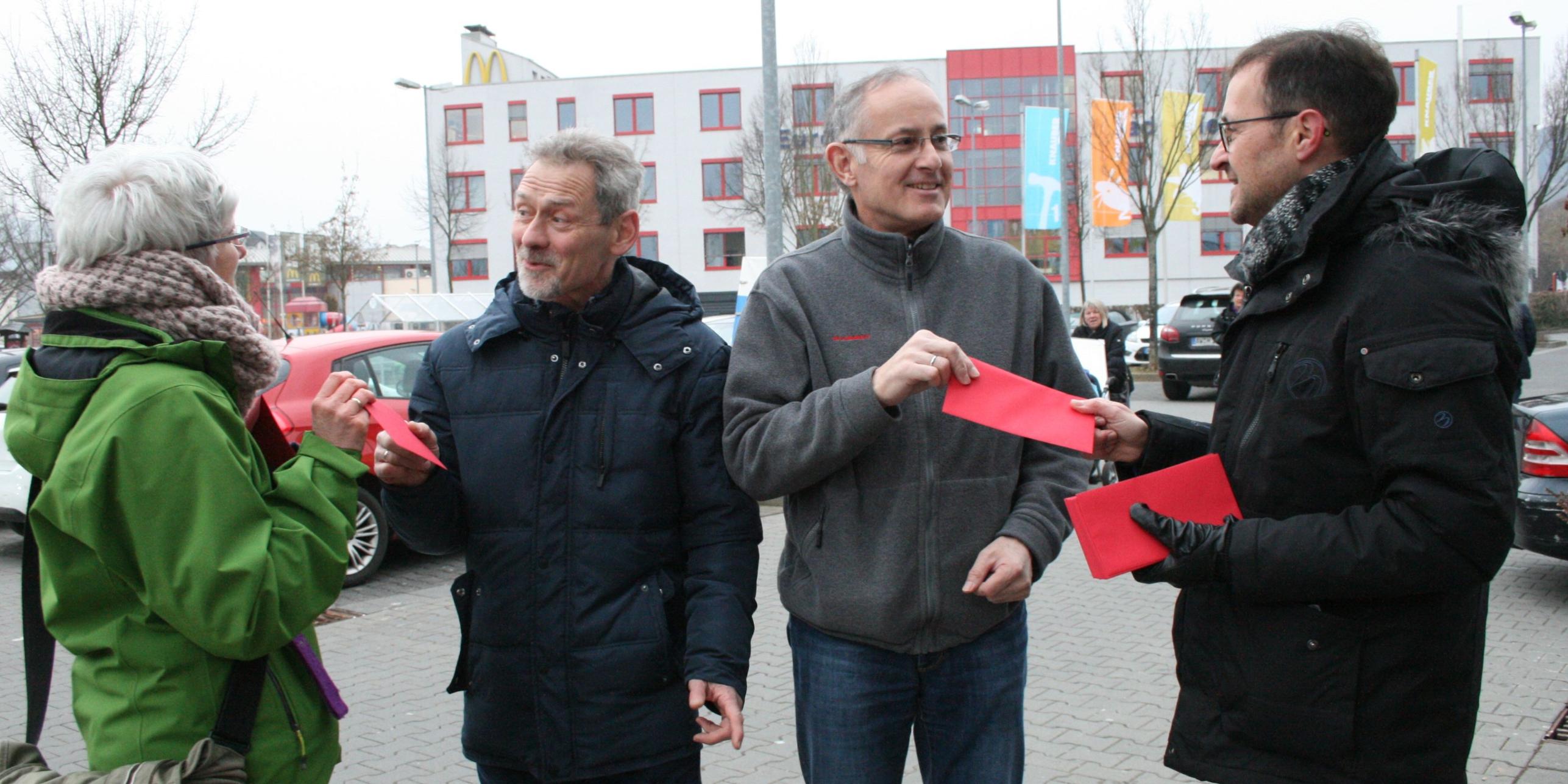 Zwei Personen verteilen Kuverts an Passanten.