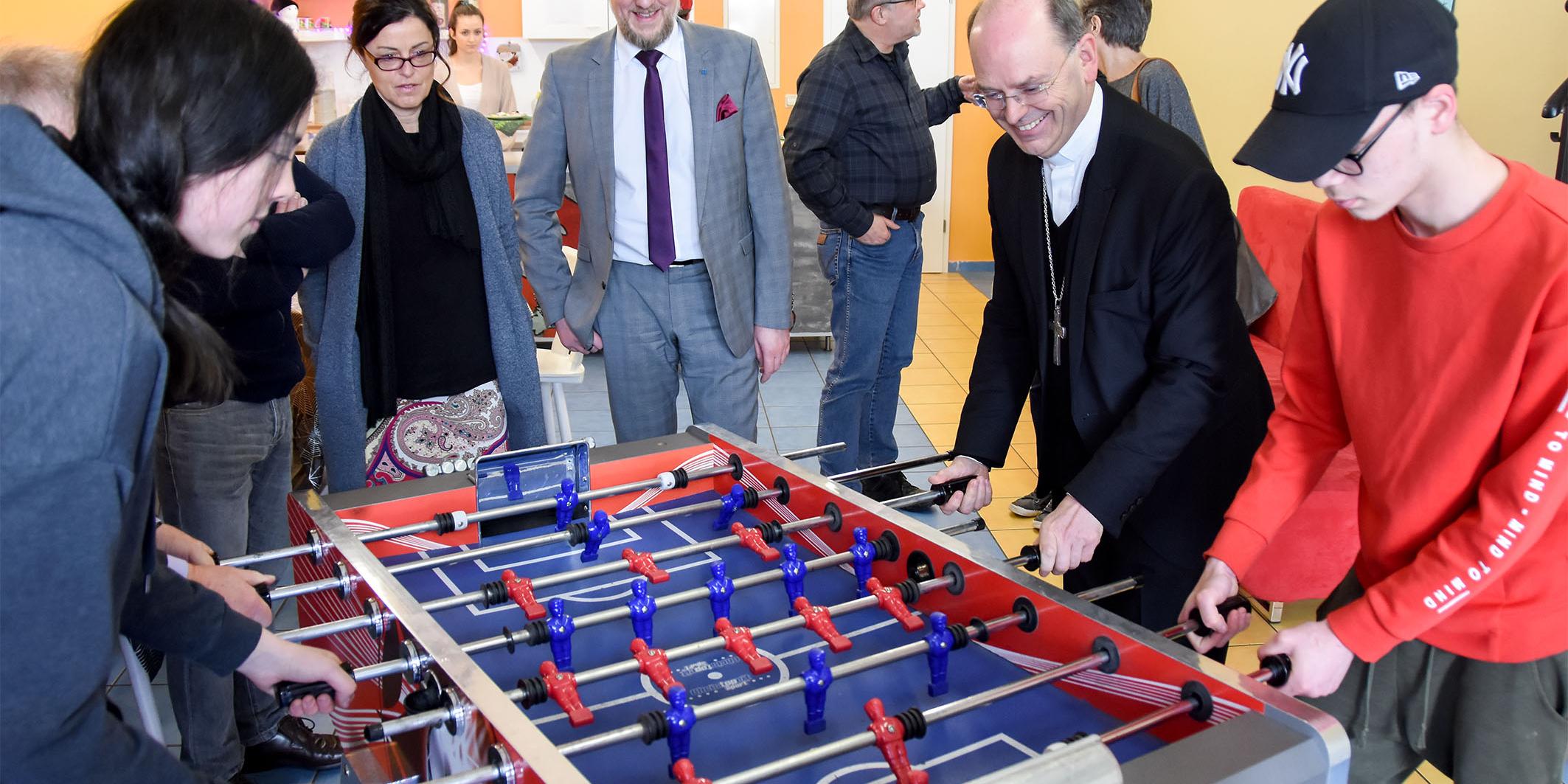 Weihbischof Robert Brahm zu Besuch im Kontaktcafé des Projekts „Respekt“ in Saarlouis. Bei einer Partie Kicker lernte er zwei junge Teilnehmer des Projekts kennen.