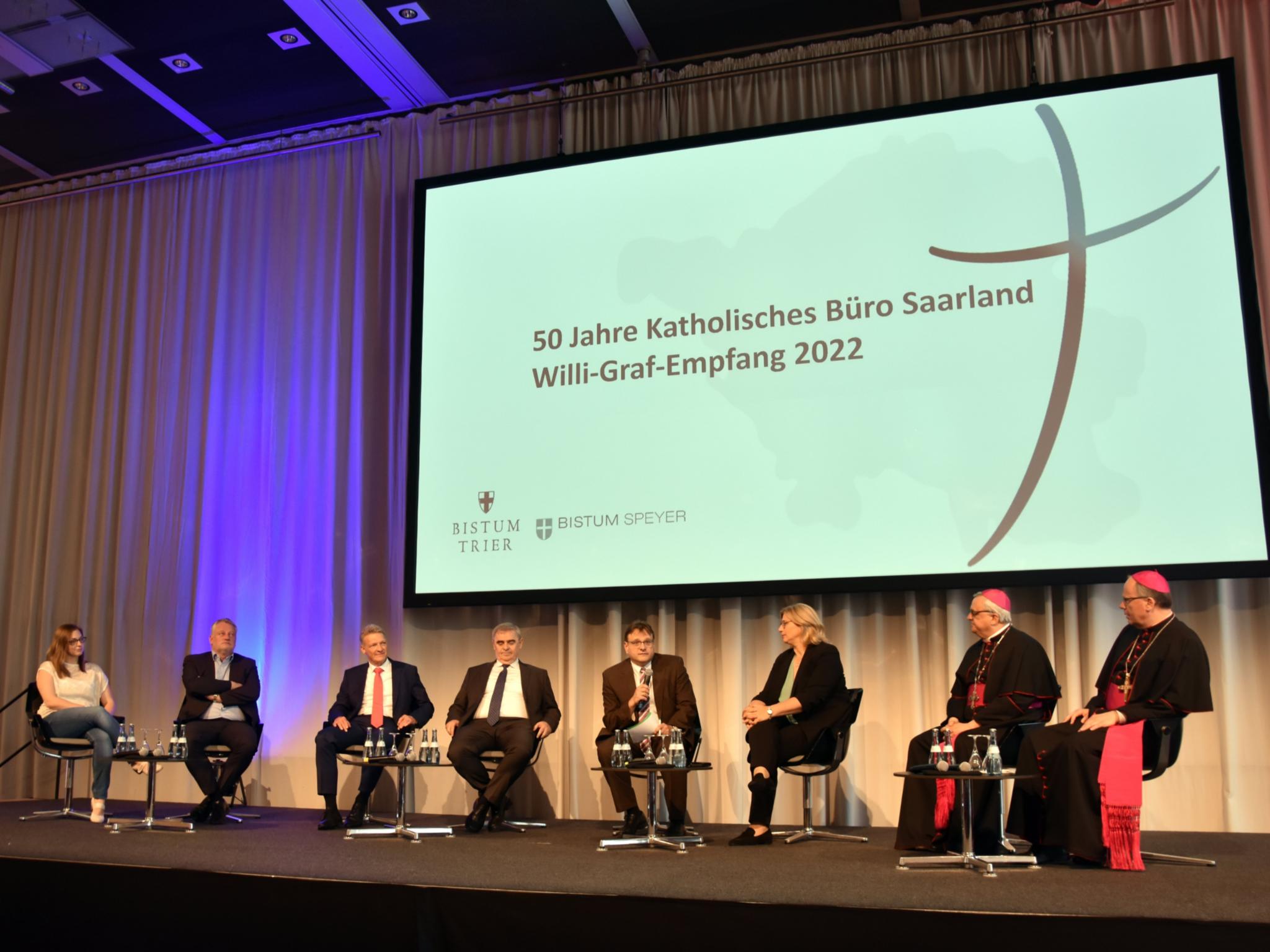 Sie diskutierten über das Verhältnis Staat und Kirche: Saska Ketterer (DJK-Bundesjugendleiterin), Ulrich Commercon (SPD-Fraktionsvorsitzender im Saar-Landtag), Stephan Toscani (Landtagspräsident a.D.), Peter Müller (Richter am Bundesverfassungsgericht), Moderator Christian Otterbach, Ministerpräsidentin Anke Rehlinger (SPD), Bischof Wiesemann und Bischof Ackermann. Foto: Ute Kirch