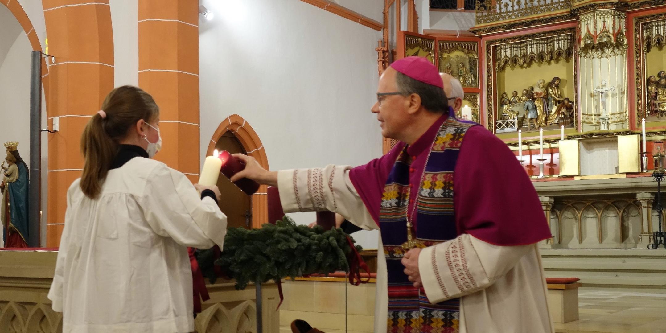 Zusammen mit einer Messdienerin zündet Bischof Ackermann die erste Kerze an (Fotos: J.Fröder/Bistum Trier)