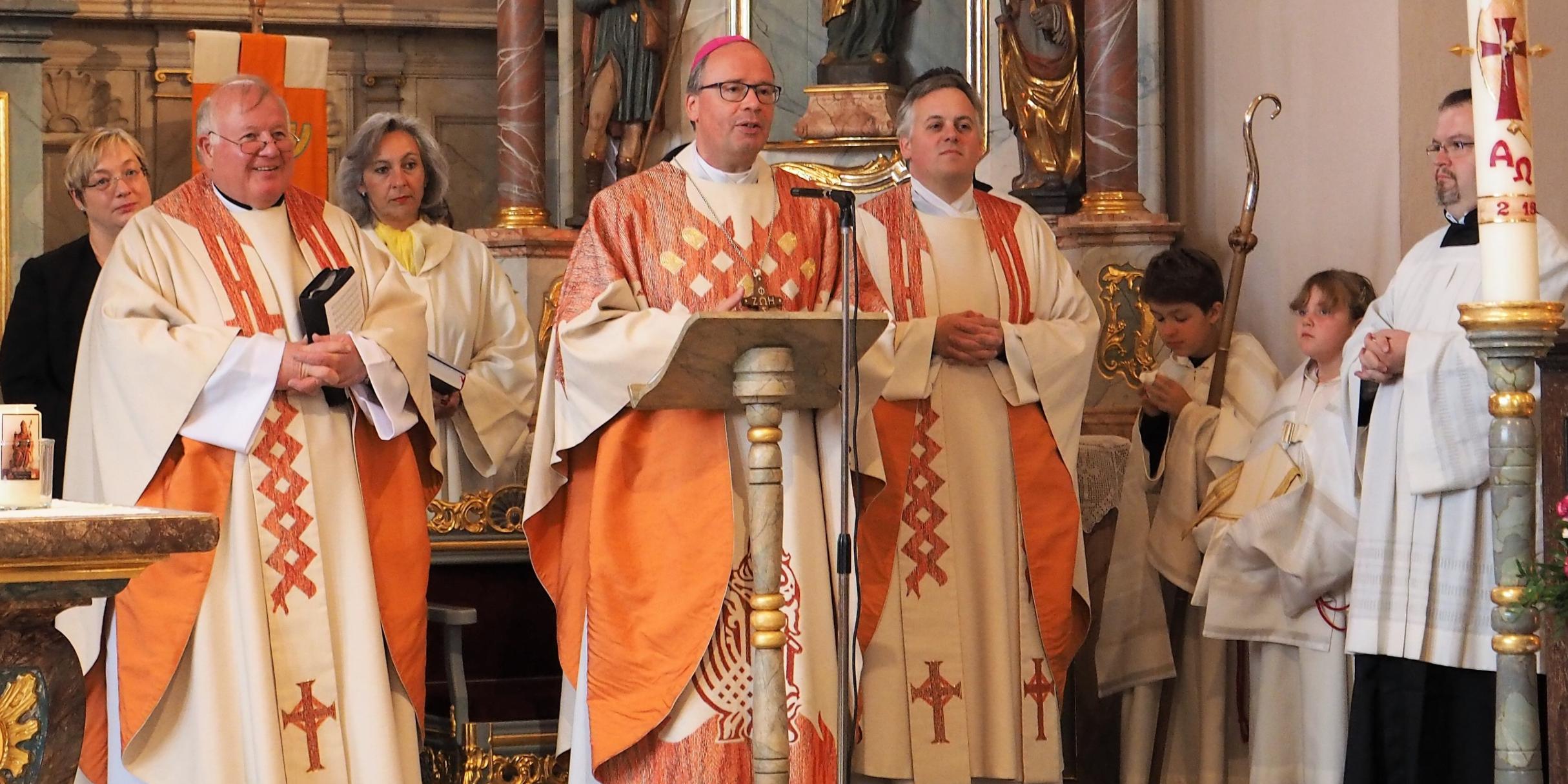 Bischof Dr. Stephan Ackermann (Mitte) mit Pfarrer Georg Josef Müller (links), Domvikar Marco Weber und Gottesdiensthelferinnen und -helfern in der Pfarrkirche St. Johannes der Täufer in Waxweiler.