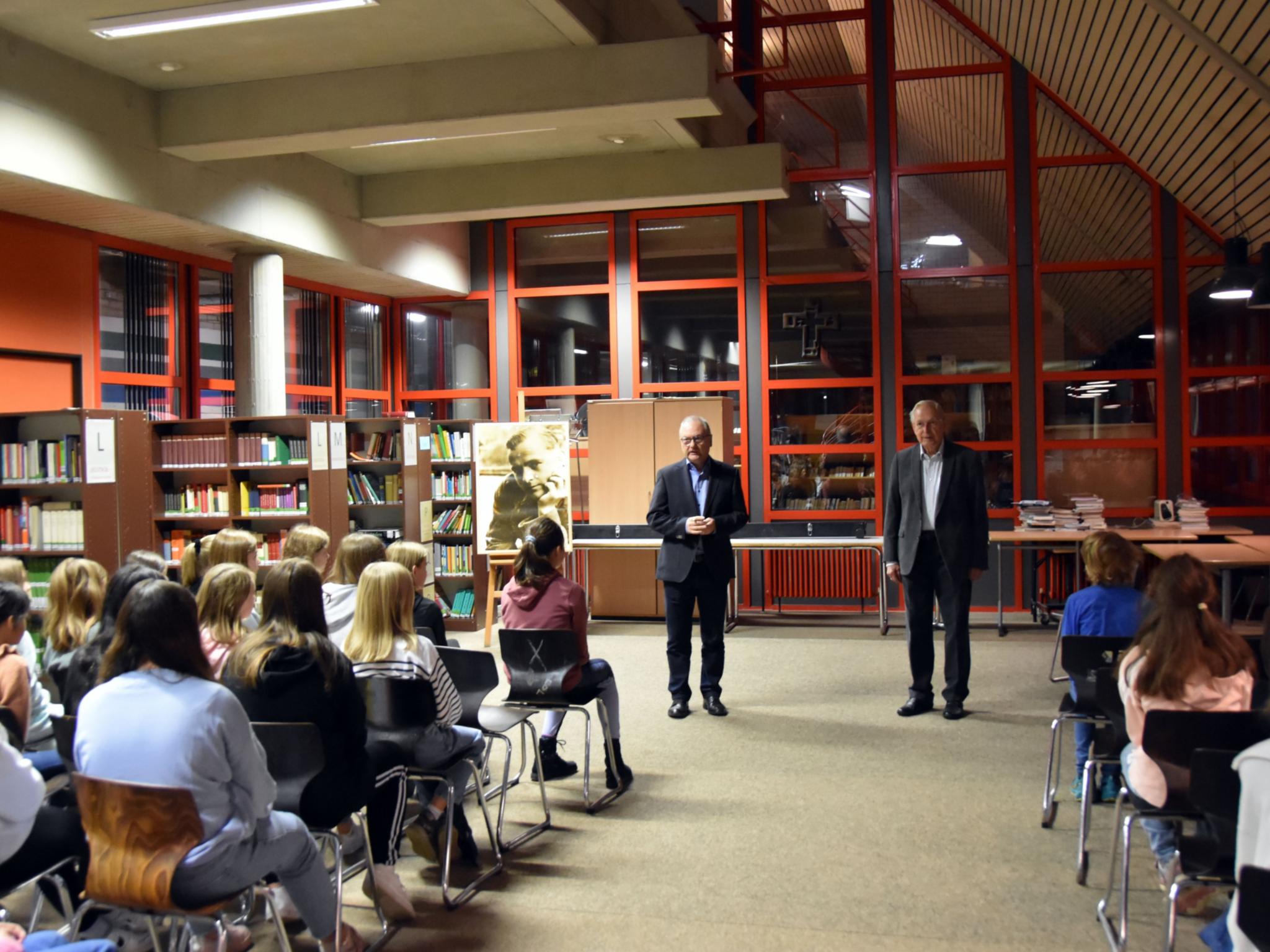 Joachim Baez und Schulleiter Stefan Kilz sprechen zu Schülerinnen und Schülern. Foto: Ute Kirch/Bistum Trier