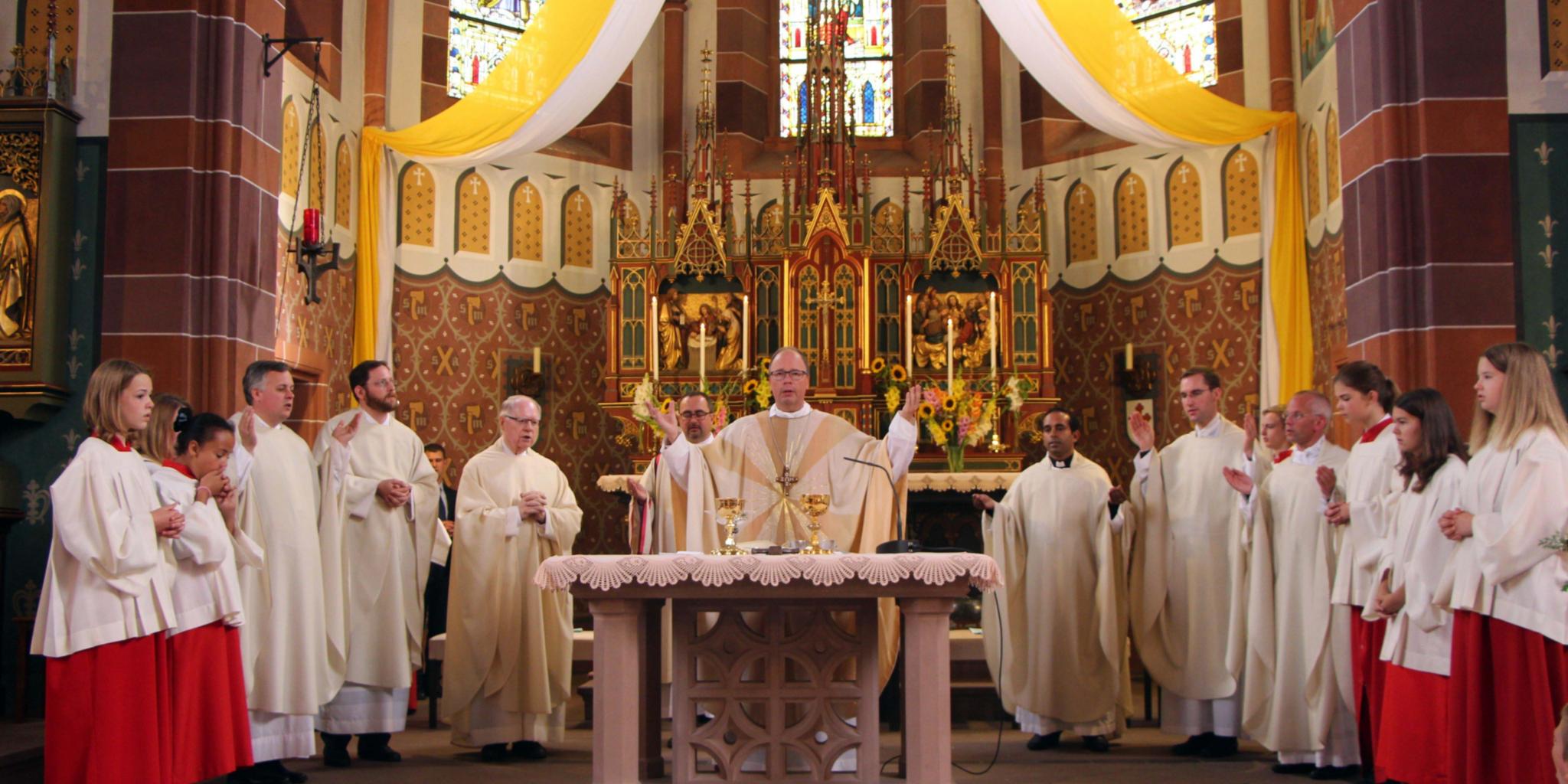 Bischof Dr. Stephan Ackermann am Altar der St. Andreas-Kirche mit (von links) den früheren Kaplänen Marco Weber und Oliver Seis, dem Ruhestandsgeistlichen Karl Kneißl, dem Diakon Andreas Maria Baumeister, dem neuen Kaplan Sabi George, dem aus Gillenfeld stammenden Kaplan Peter Zillgen und Ortspfarrer Carsten Rupp.