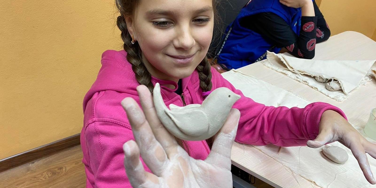 Ein kleines ukrainisches Mädchen hält eine Friedenstaube hoch (Foto: Caritas international)