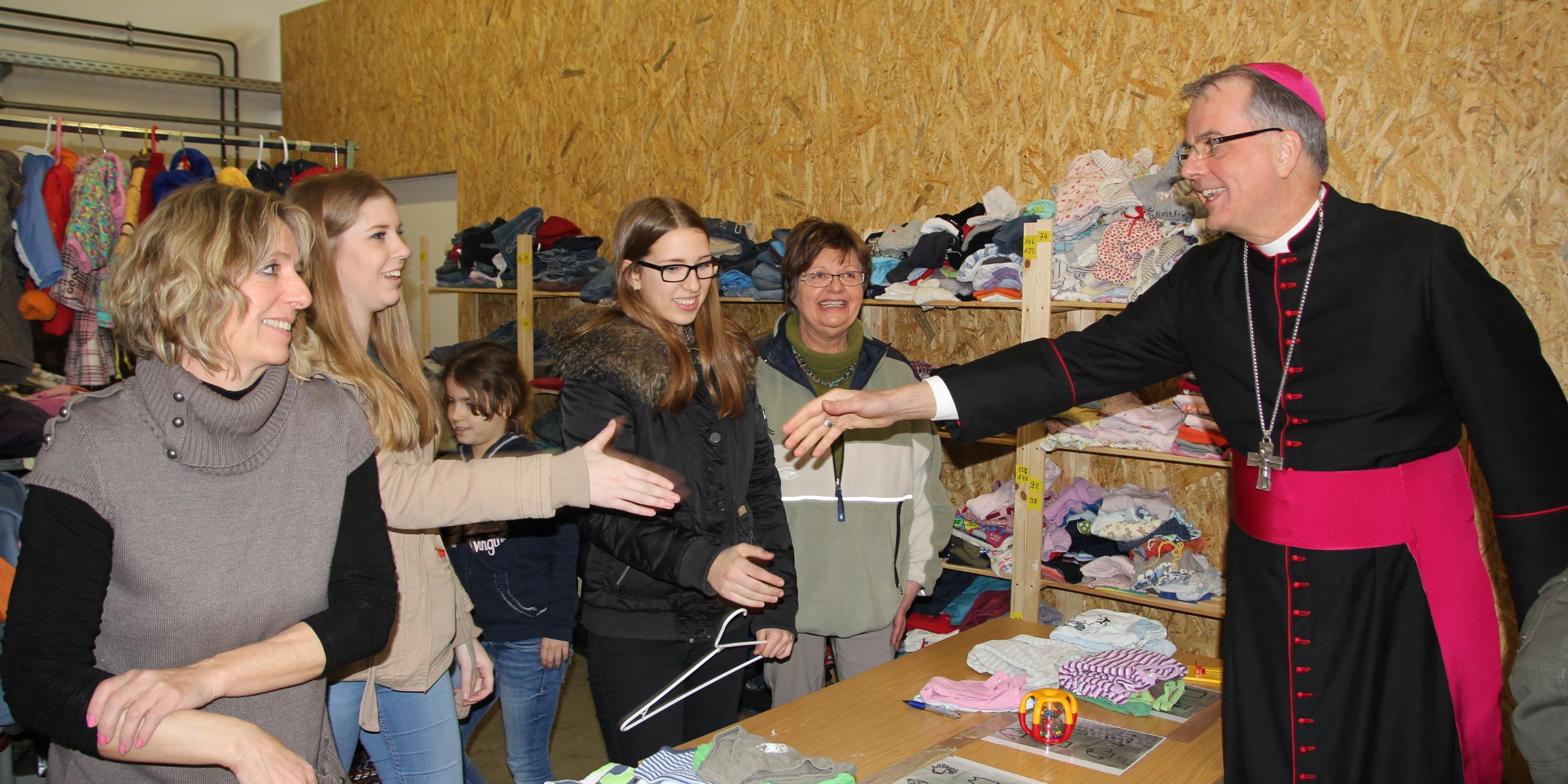 Weihbischof Peters hat die Ehrenamtlichen getroffen, die sich in der Kleiderkammer seit Monaten für Flüchtlinge engagieren.