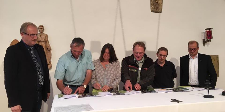 Partner unterzeichnen die Kooperation: Ortsbürgermeister Peter Kretz, Bernd Schmitt, Verein Dorf und Kirche im Nationalpark, Umweltministerin Ulrike Höfken, Harald Egidi, Nationalparkamt, Dechanten Clemens Kiefer (Birkenfeld) und Clemens Grünebach (Hermeskeil) (von links).