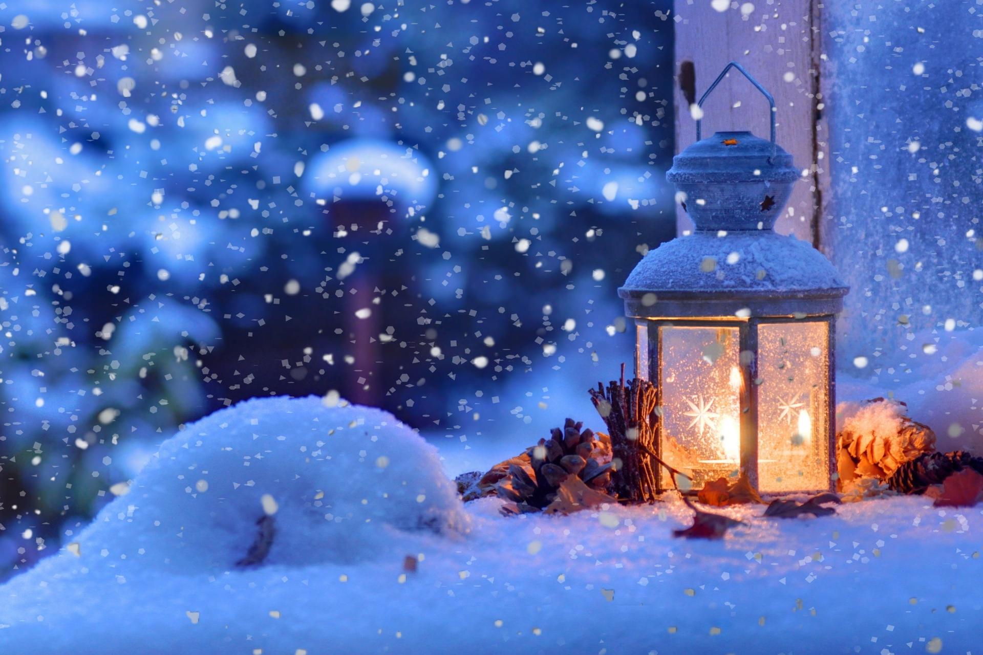Auf dem Titelbild des diesjährigen Adventskalenders ist eine verschneite Laterne, vor einem Fenster in weihnachtlicher Abendstimmung zu sehen.