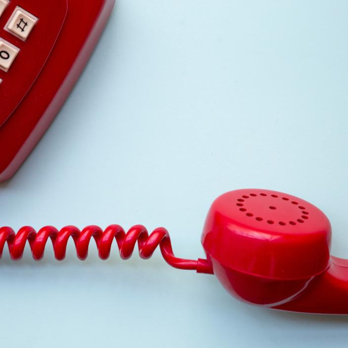 Ein rotes Telefon mit einem hellblauen Hintergrund