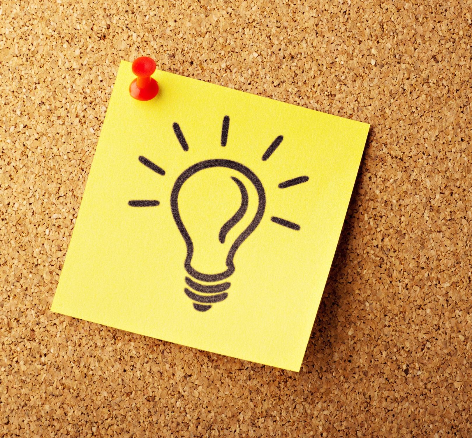 Korkpinnwand mit gelbem Post-it-Zettel, auf den eine Glühbirne gezeichnet ist