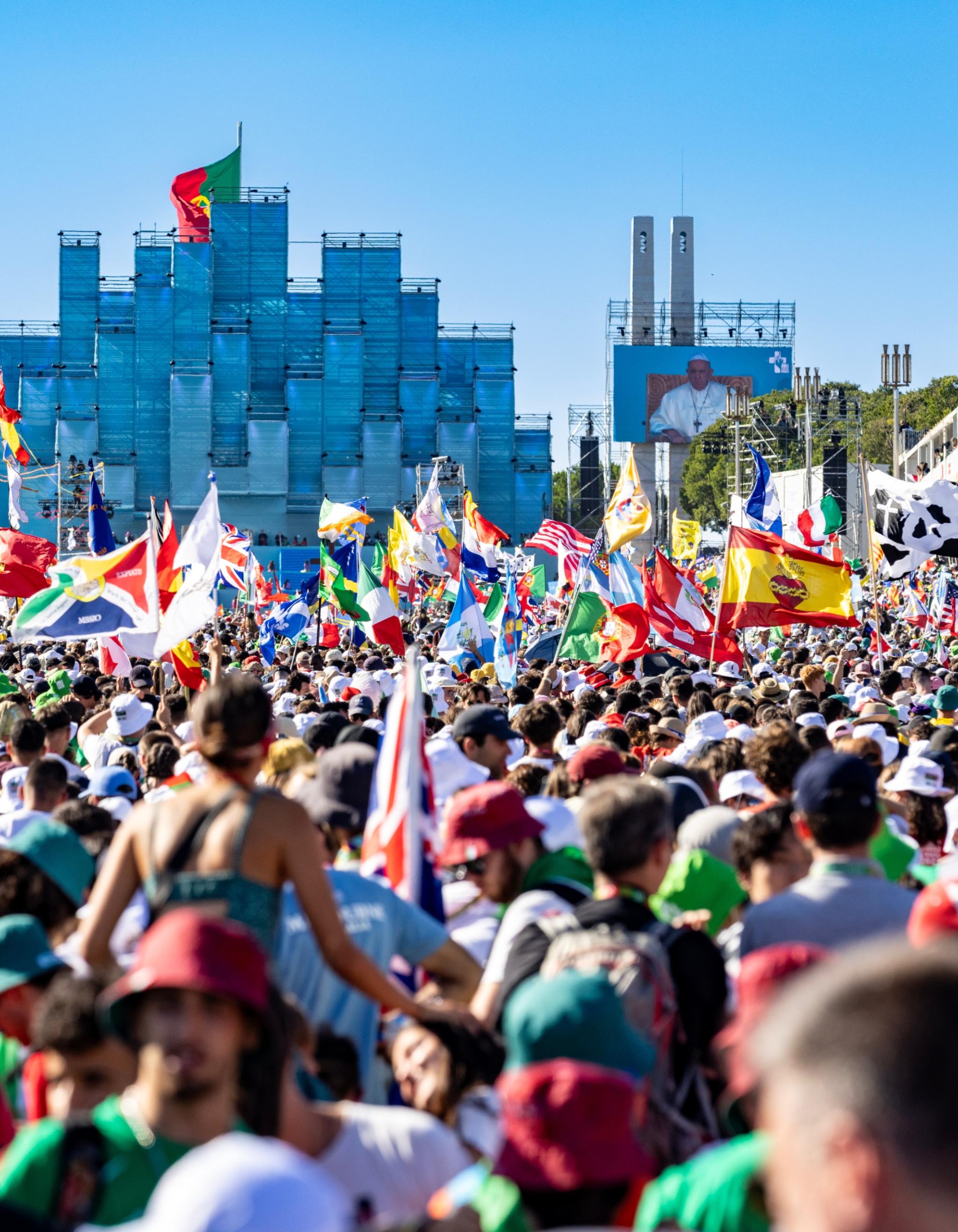 Menschenmenge auf dem Weltjugentag 2023 in Portugal, einige Personen schwenken bunte Landesflaggen