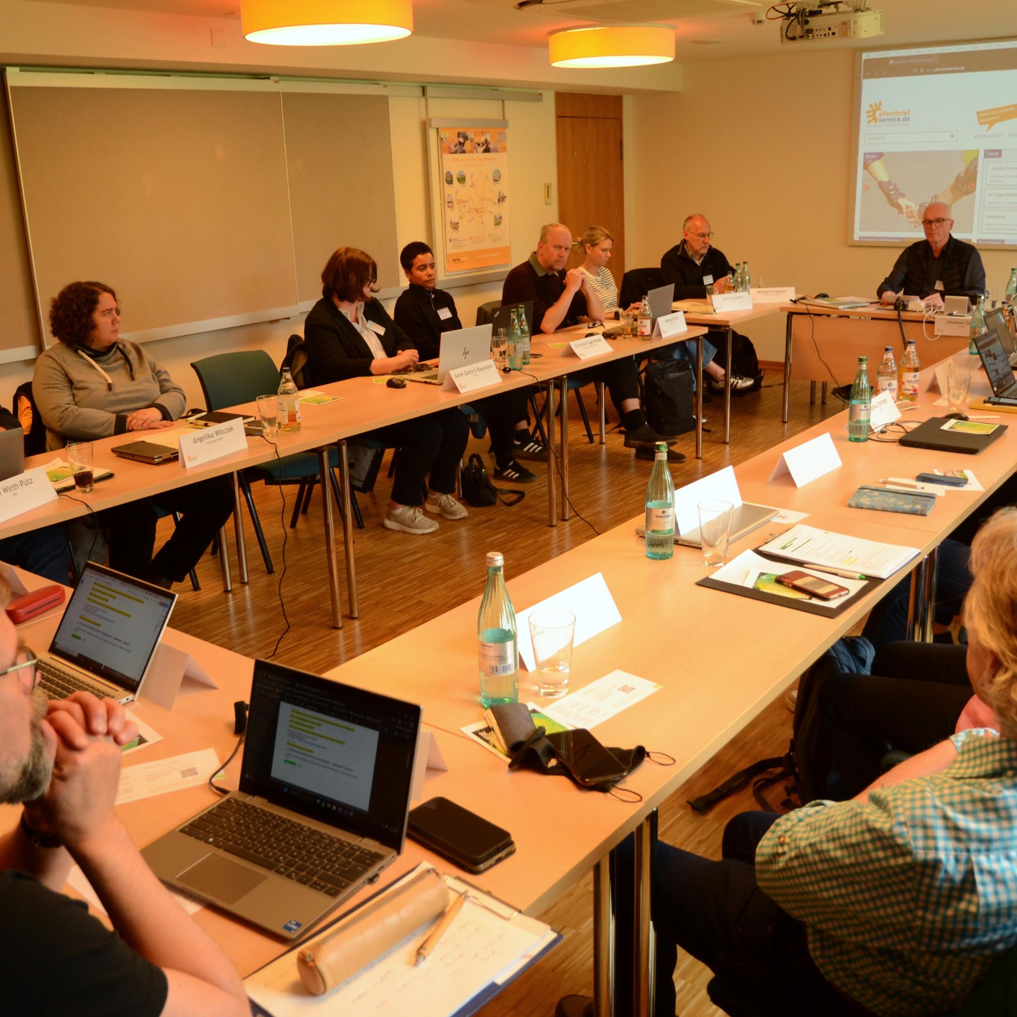 Zum letzten Mal in diesem Setting: Johannes Simon (vor der Leinwand) moderierte die Bundeskonferenz 2025 von Pfarrbriefservice.de. Er wird im Oktober 2025 in den Ruhestand gehen.