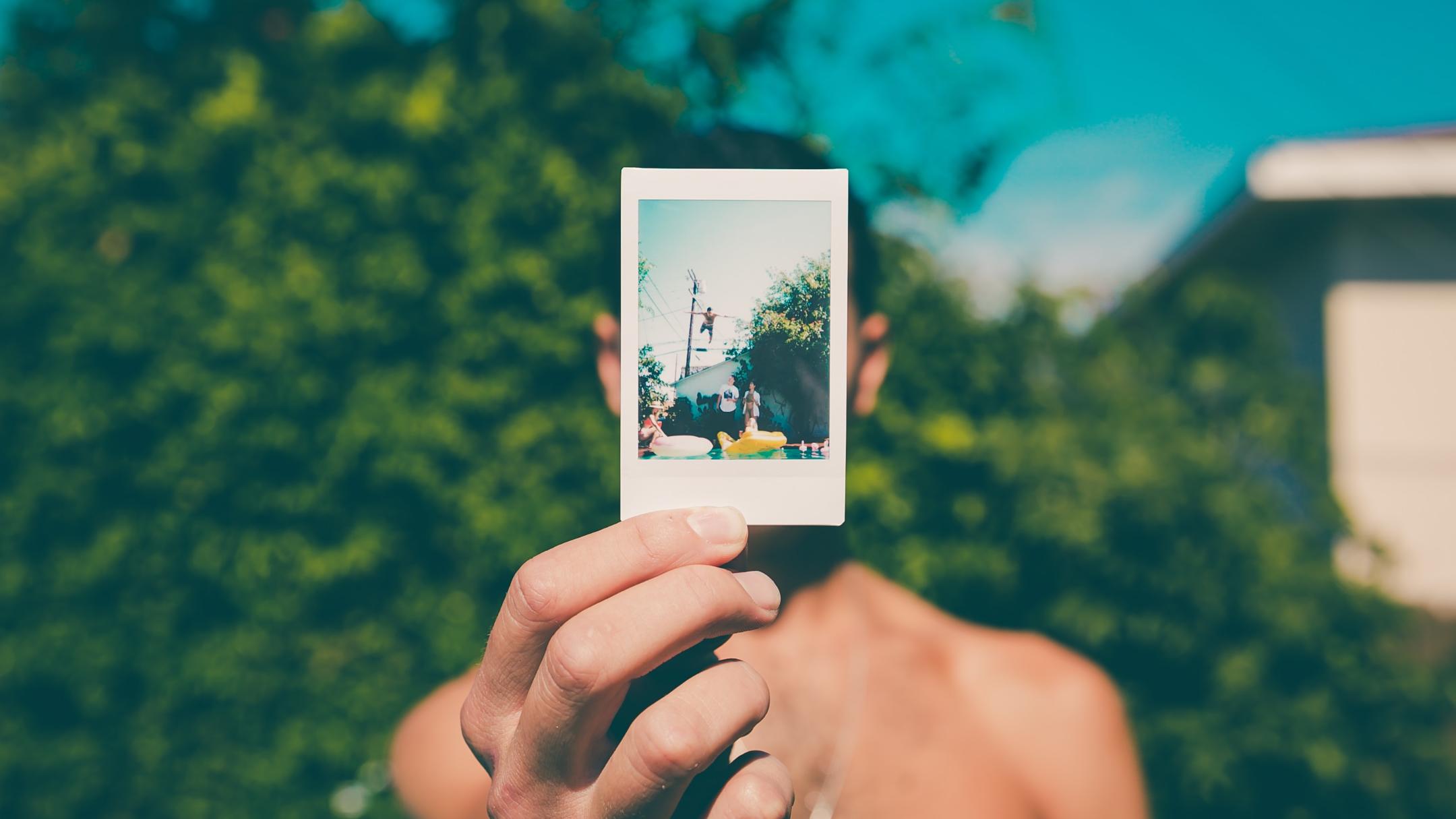 Eine Hand hält ein Polaroid-Foto in die Kamera