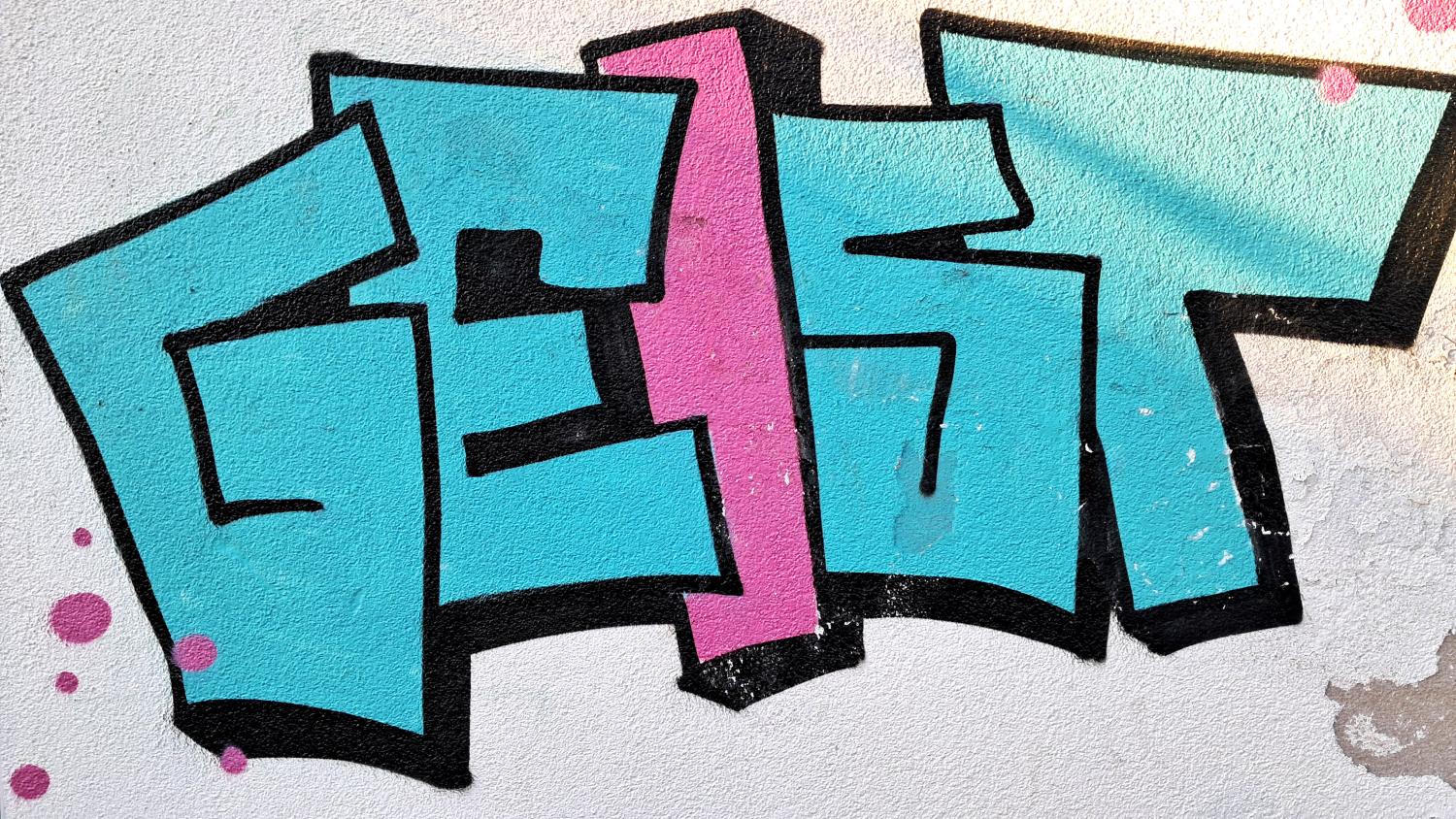 Buntes Graffiti mit dem Wort 'GEIST' in Blau und Rosa auf einer weißen Wand.