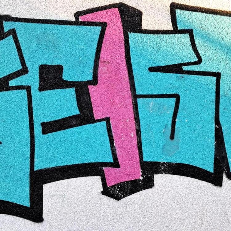Buntes Graffiti mit dem Wort 'GEIST' in Blau und Rosa auf einer weißen Wand.