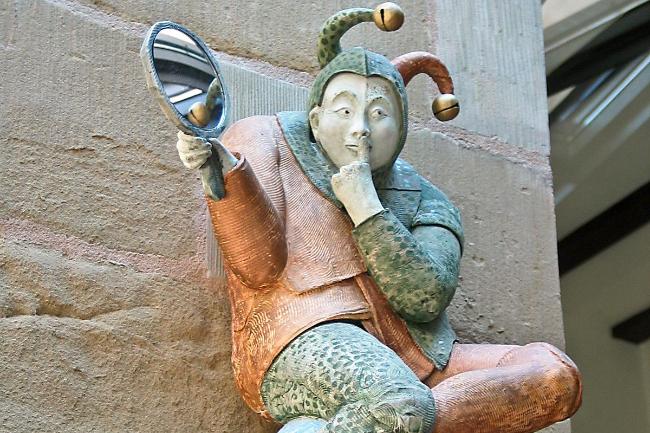 Die Skulptur eines Narren, der auf einer Erdkugel sitzt