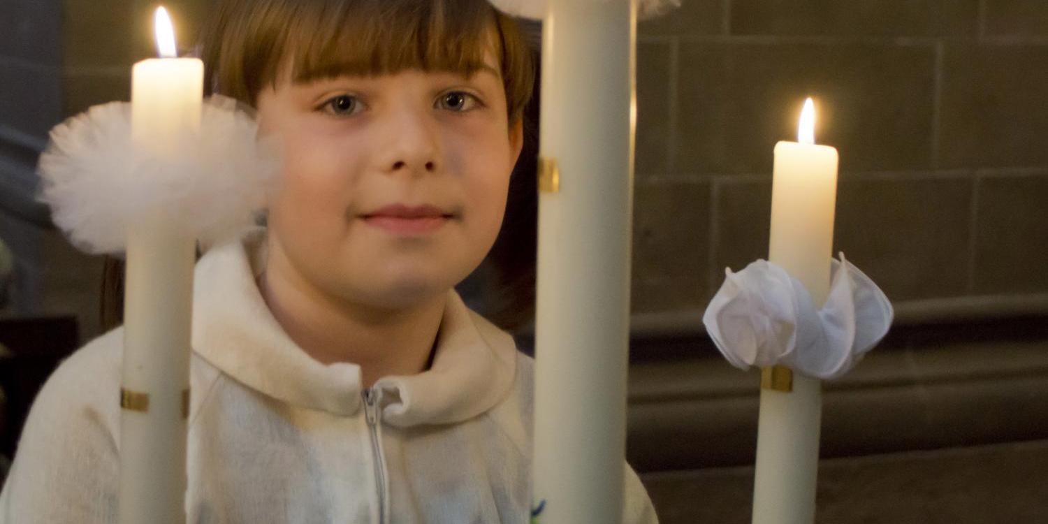 Ein Mädchen hält eine brennende Kerze.