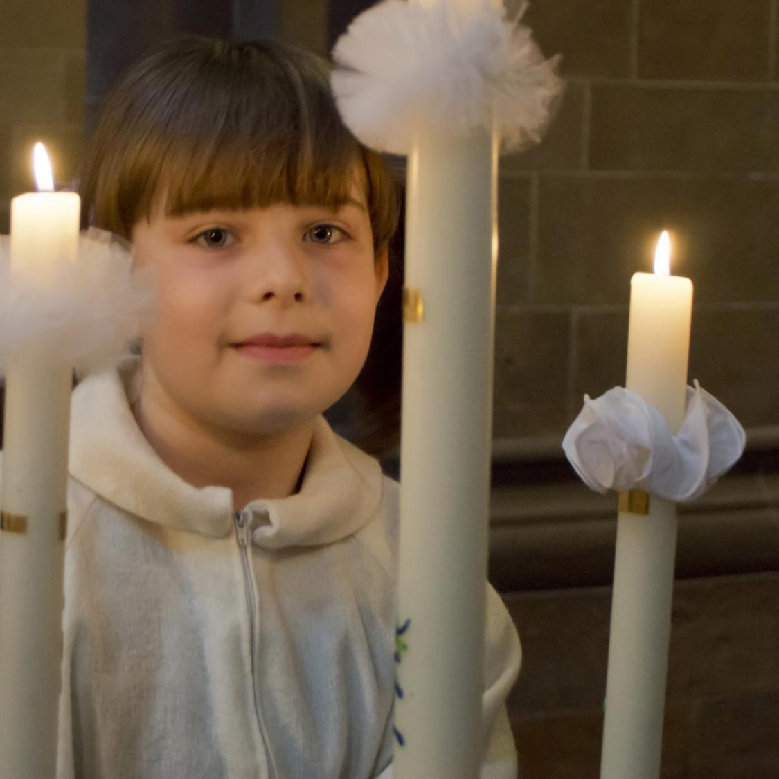 Ein Mädchen hält eine brennende Kerze.