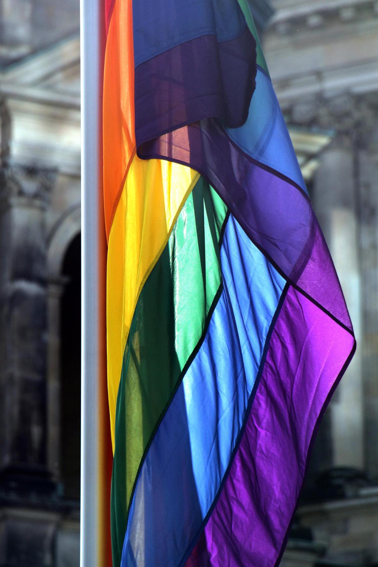 Eine Regenbogenfahne vor einem alten Gemäuer