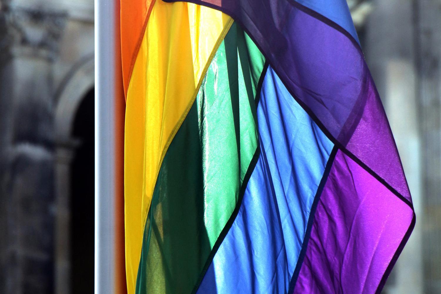 Eine Regenbogenfahne vor einem alten Gemäuer