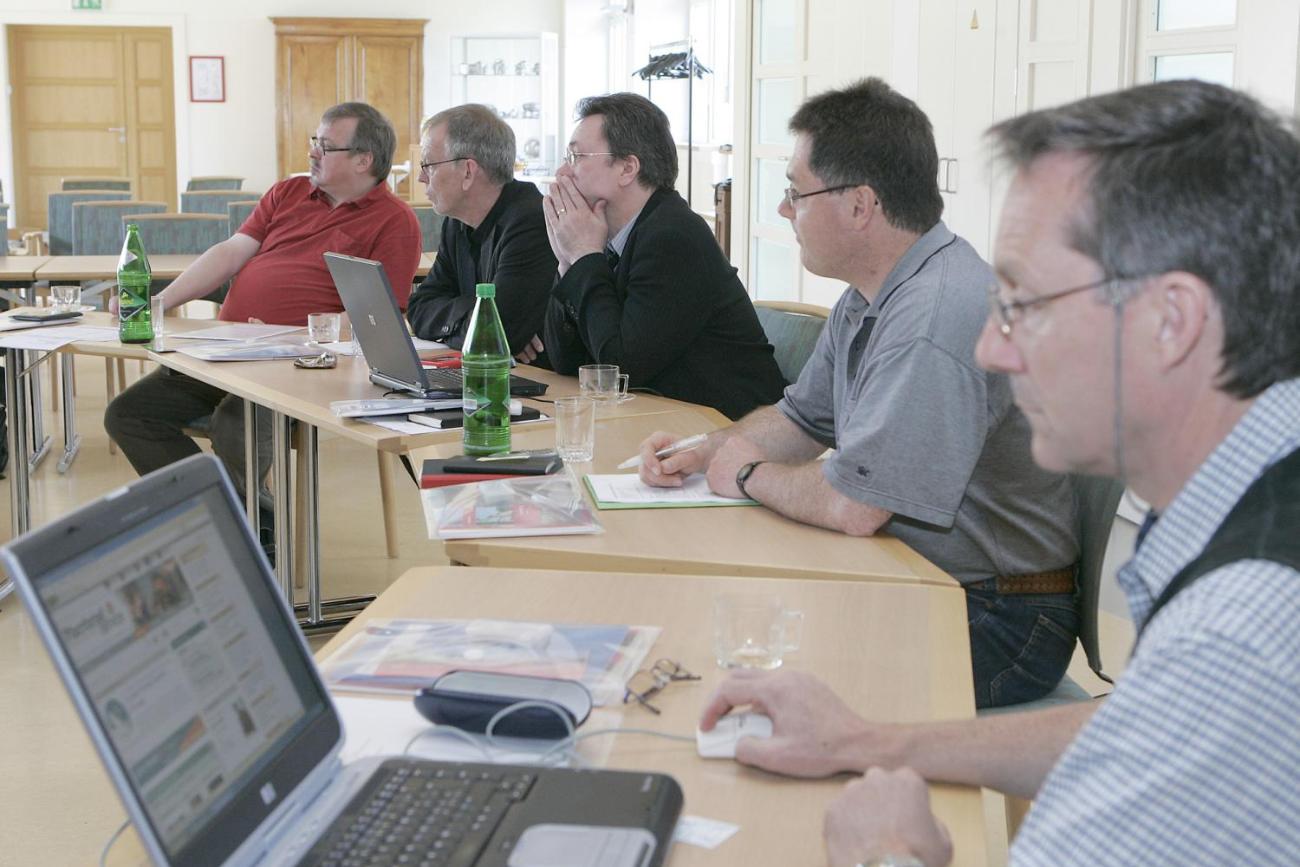 Männer sitzen mit ihren Laptops an einem Tisch