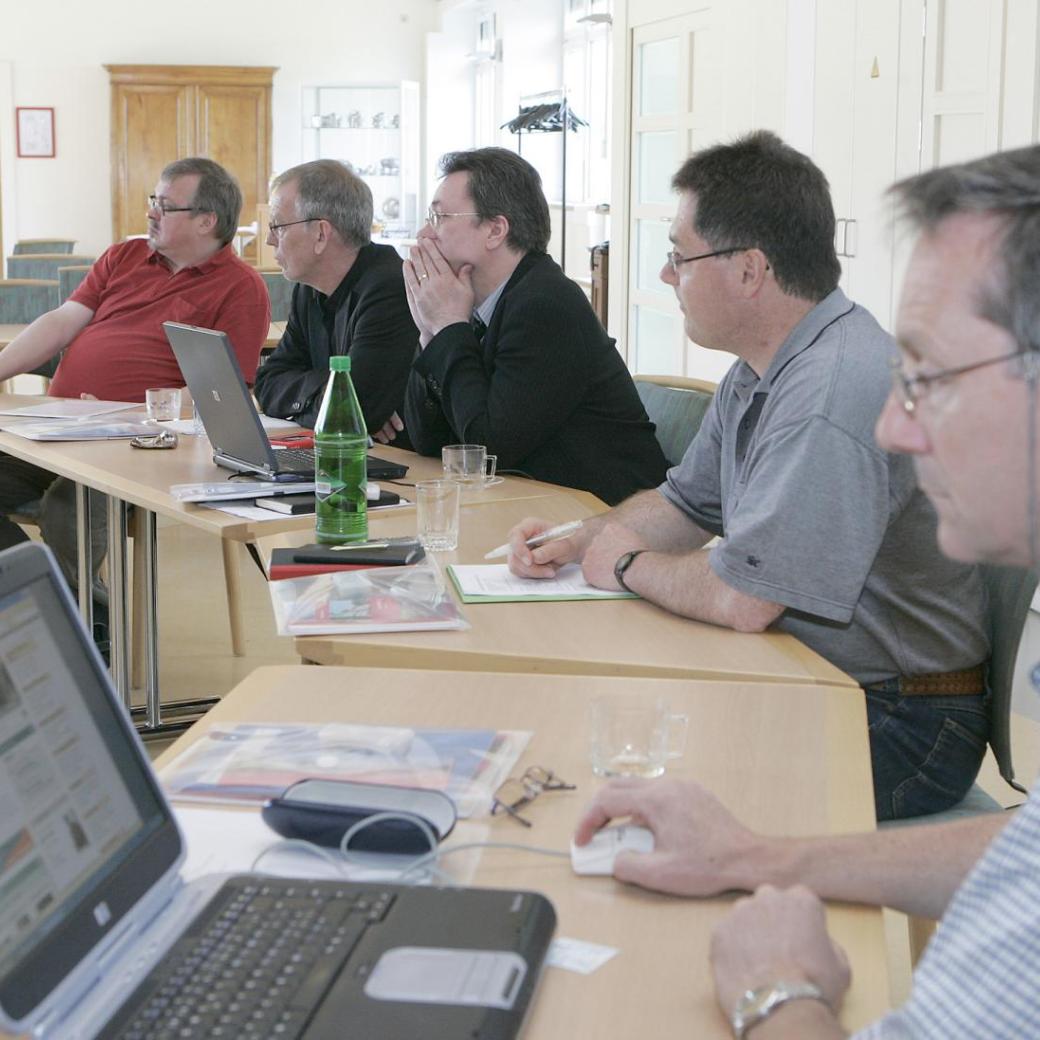 Männer sitzen mit ihren Laptops an einem Tisch