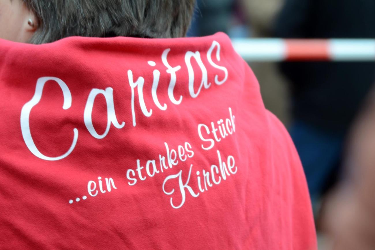 Ein Mensch mit einem Pullover mit der Aufschrift: Caritas - ein starkes Stück Kirche