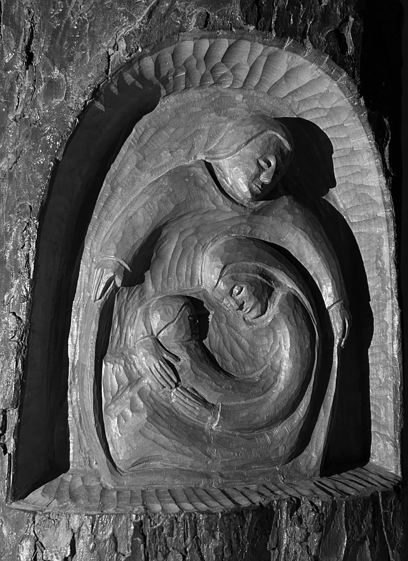 Eine Krippengruppe, die in einen Baumstamm geschnitzt wurde.