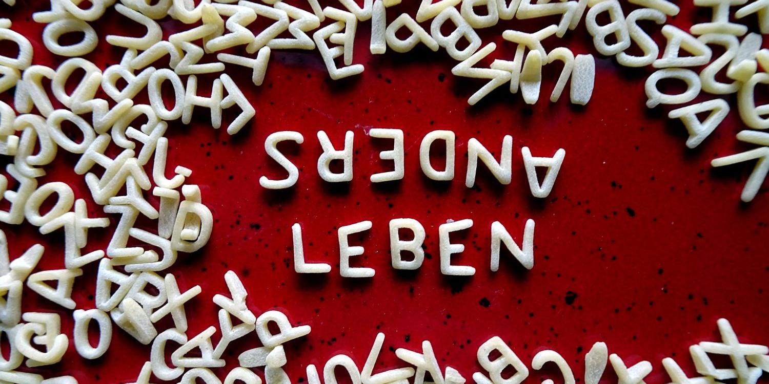 Buchstabennudeln bilden die Worte 'Anders leben'