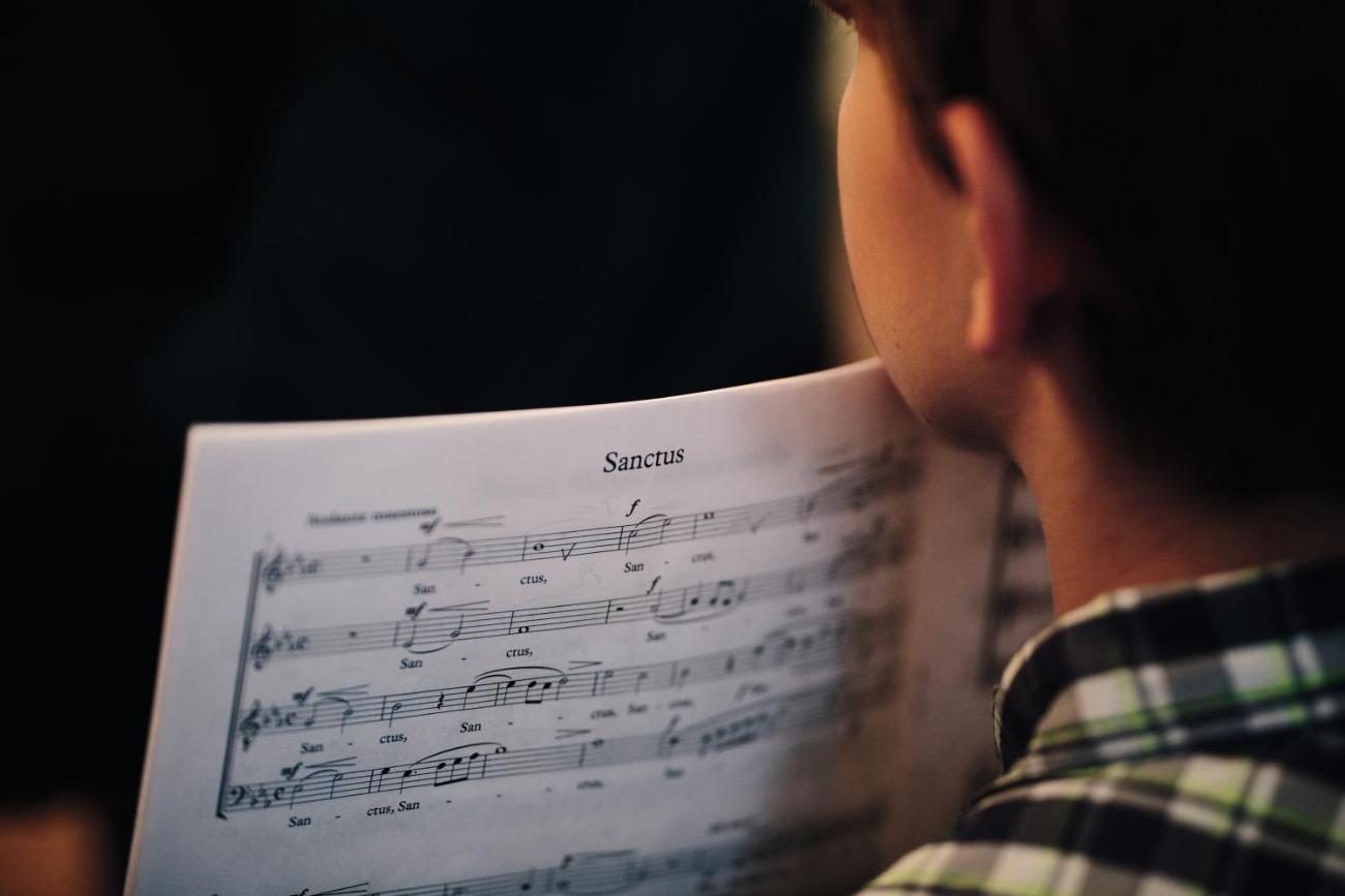 Ein junger Sänger blickt auf ein Notenblatt.