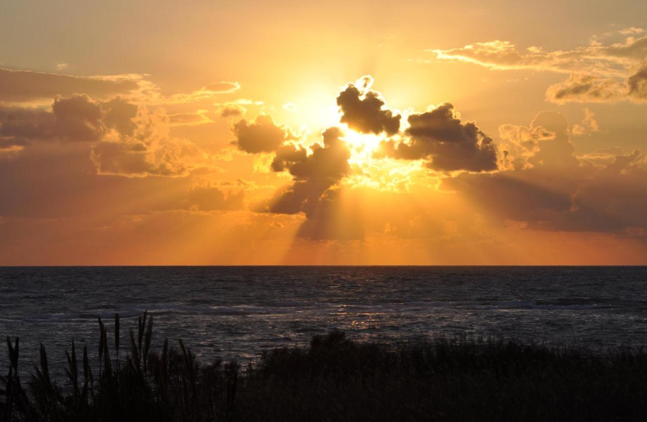 Sonnenuntergang über dem Meer mit Wolken und goldenen Strahlen
