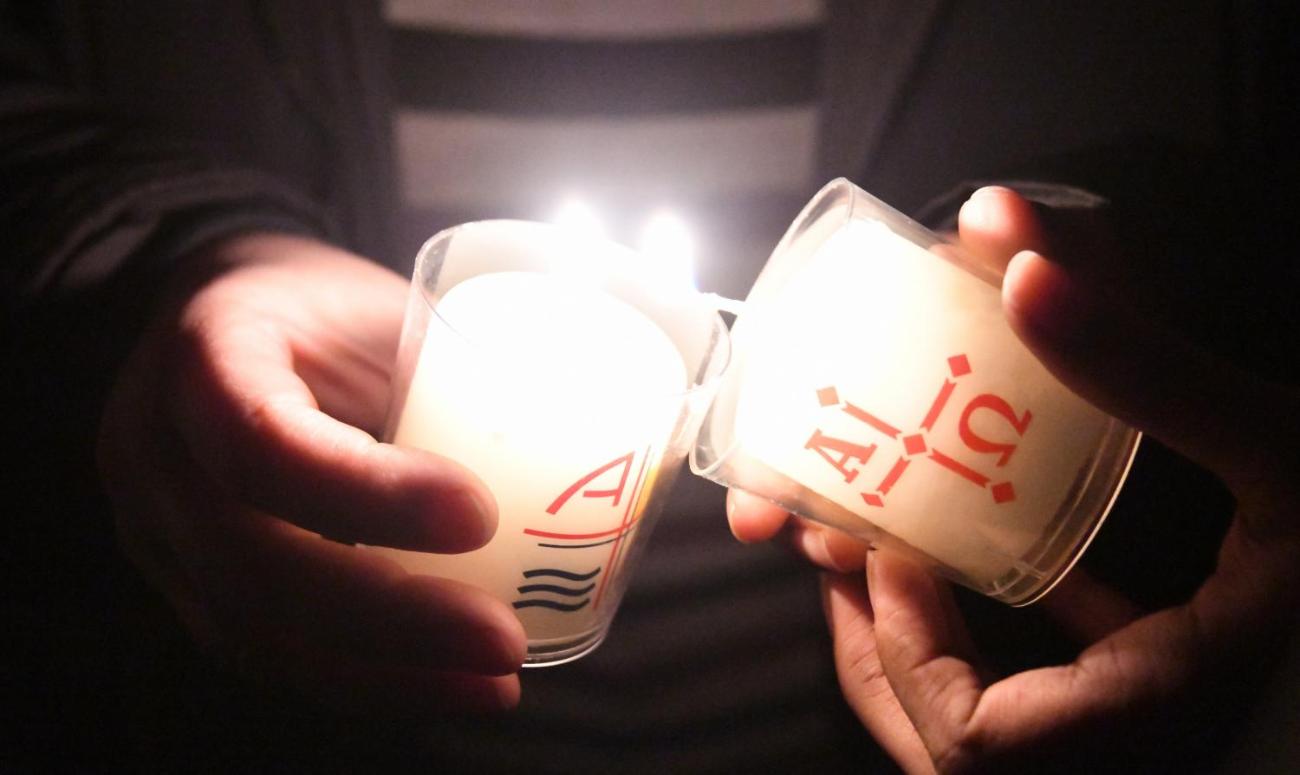 Eine Kerze wird an einer anderen Kerze entzündet.