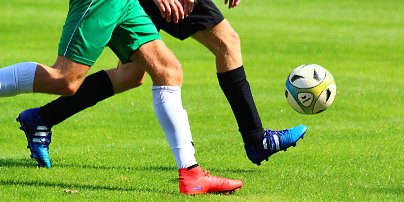 Zwei Männer laufen einem Fußball hinterher.